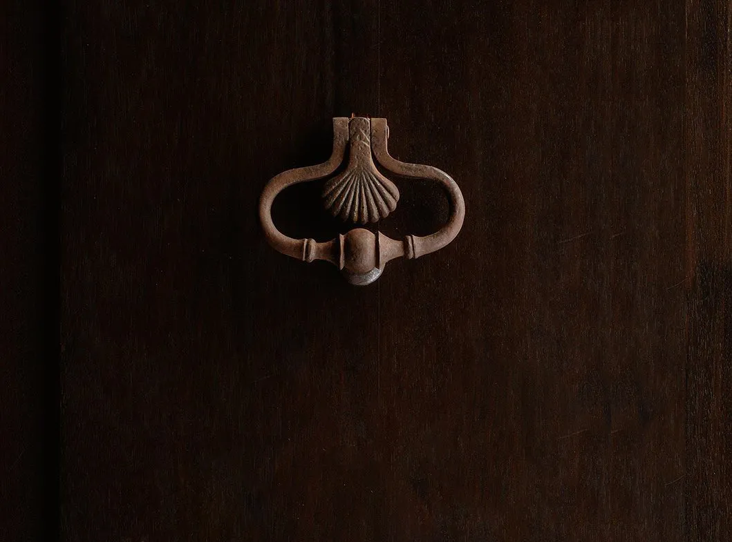 Heritage brass door knocker — honest materials and refined detail beside John Meng’s collectible ashtray design language.